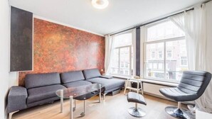Ett modernt vardagsrum med en grå soffa, ett soffbord i glas och en svart stol.