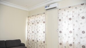 A room with a grey sofa, beige walls, and patterned curtains. - Luxuriously Finished 4-bed House in Tema Comm 25 (Tema)