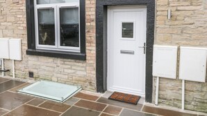 A stone building with a white door, a window with a black frame, and a glass door mat. - Moor View (Skipton)