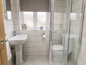 A modern bathroom with a white sink, toilet, and shower. - Moor View (Skipton)