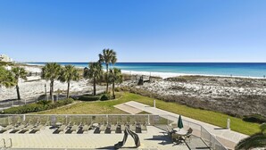 Blick auf einen Strand mit einer Terrasse, die Stühle und eine überdachte Sitzgelegenheit bietet.
