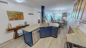 Eine moderne Küche mit eingebautem Geschirrspüler, einem Holzespeisetisch und Meerblick.