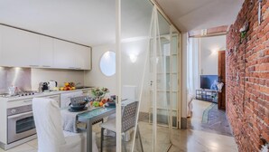 A modern kitchen with white cabinets, a dining table with chairs, and a glass partition. - Casta Dama Apartment (Lucca)