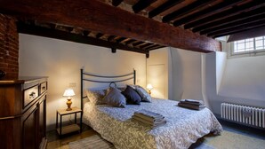 A bedroom with a bed, two bedside tables with lamps, a wooden dresser, and a radiator. - Casta Dama Apartment (Lucca)