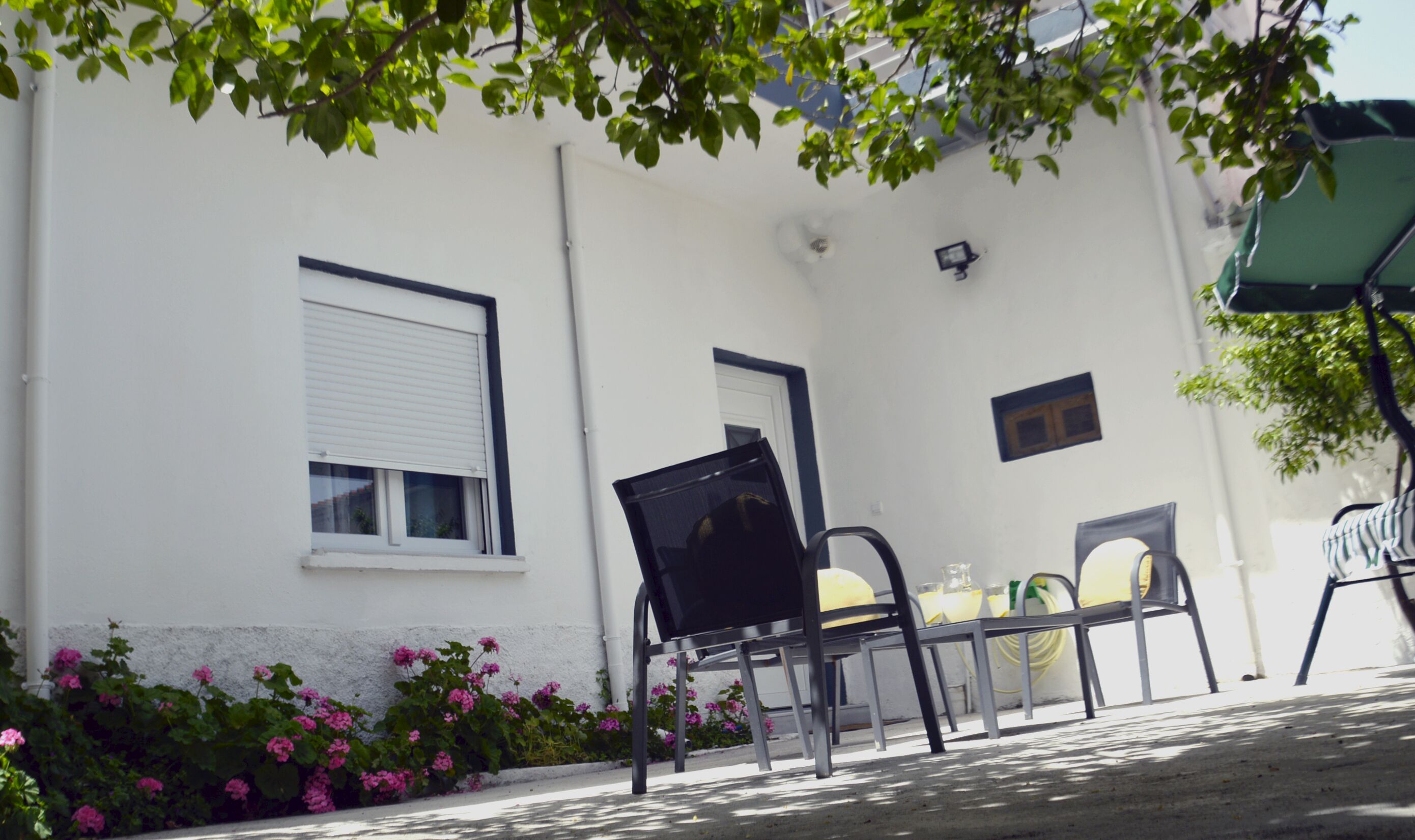 A white building with a window, a door, and a black chair outside.