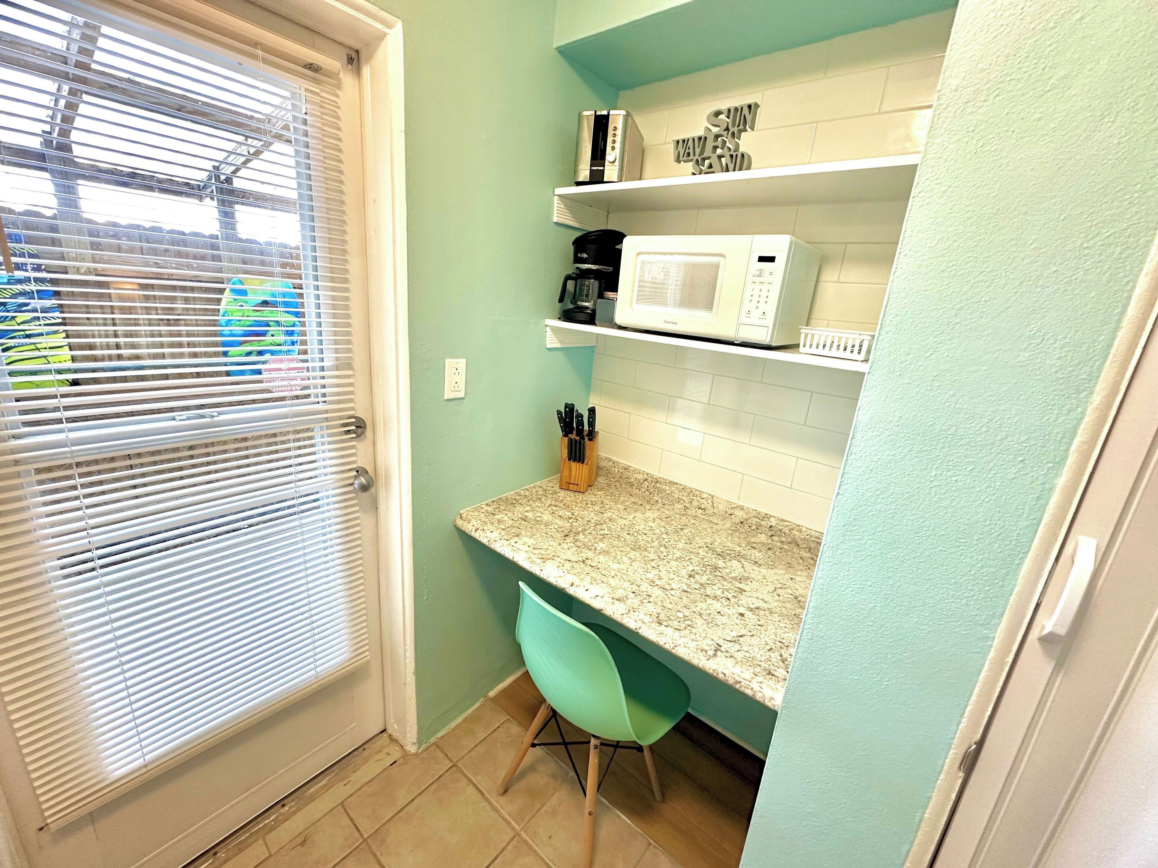 A kitchen with a microwave, a coffee maker, and a knife block on the counter.