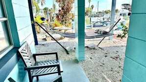A porch with a wooden bench and a hammock.