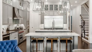 A modern kitchen with a central island, stainless steel appliances, and pendant lighting. - Villatel Luxury Homes at Reunion Resort (Kissimmee)