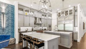 A modern kitchen with white cabinetry, stainless steel appliances, and a central island. - Villatel Luxury Homes at Reunion Resort (Kissimmee)