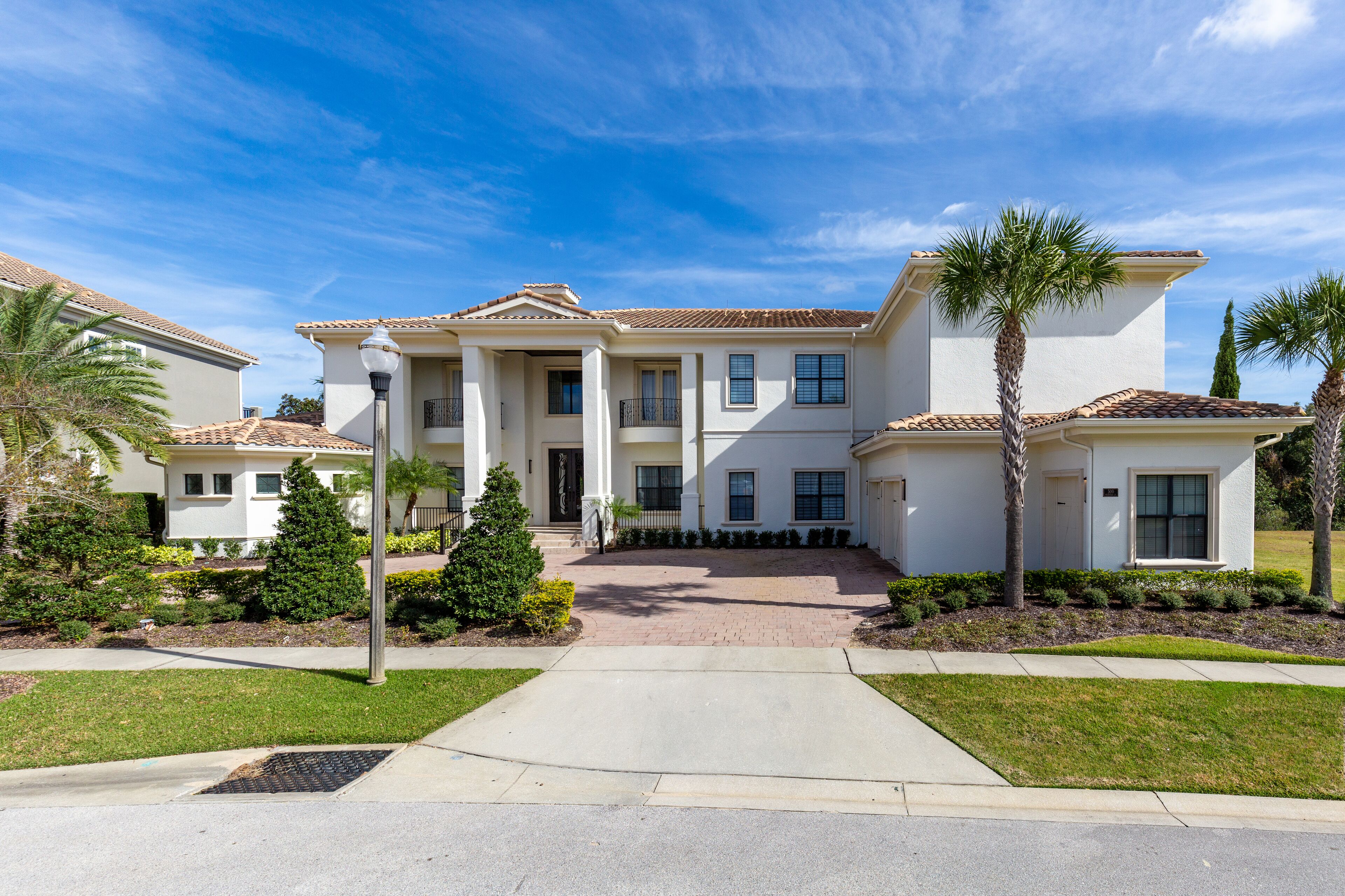 A two-story house with a tiled roof, a front porch, and a driveway leading to the entrance.