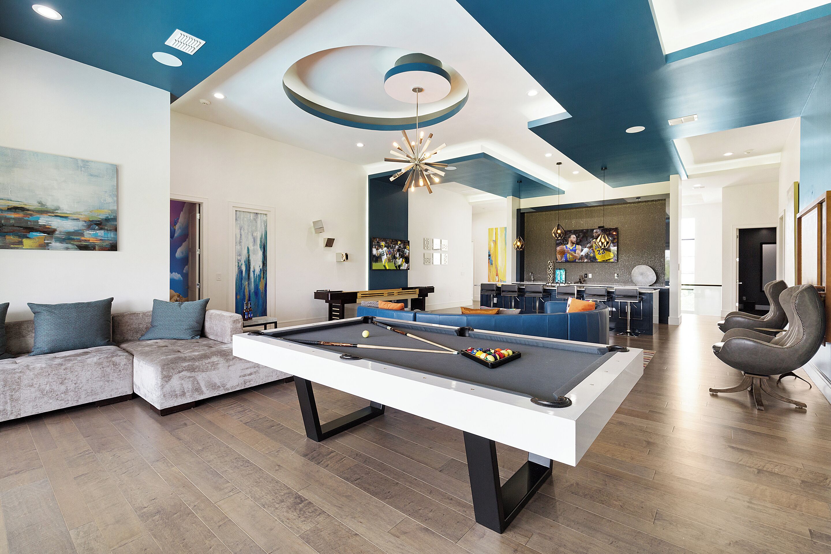 A modern living room with a pool table, a sofa, and a bar area.