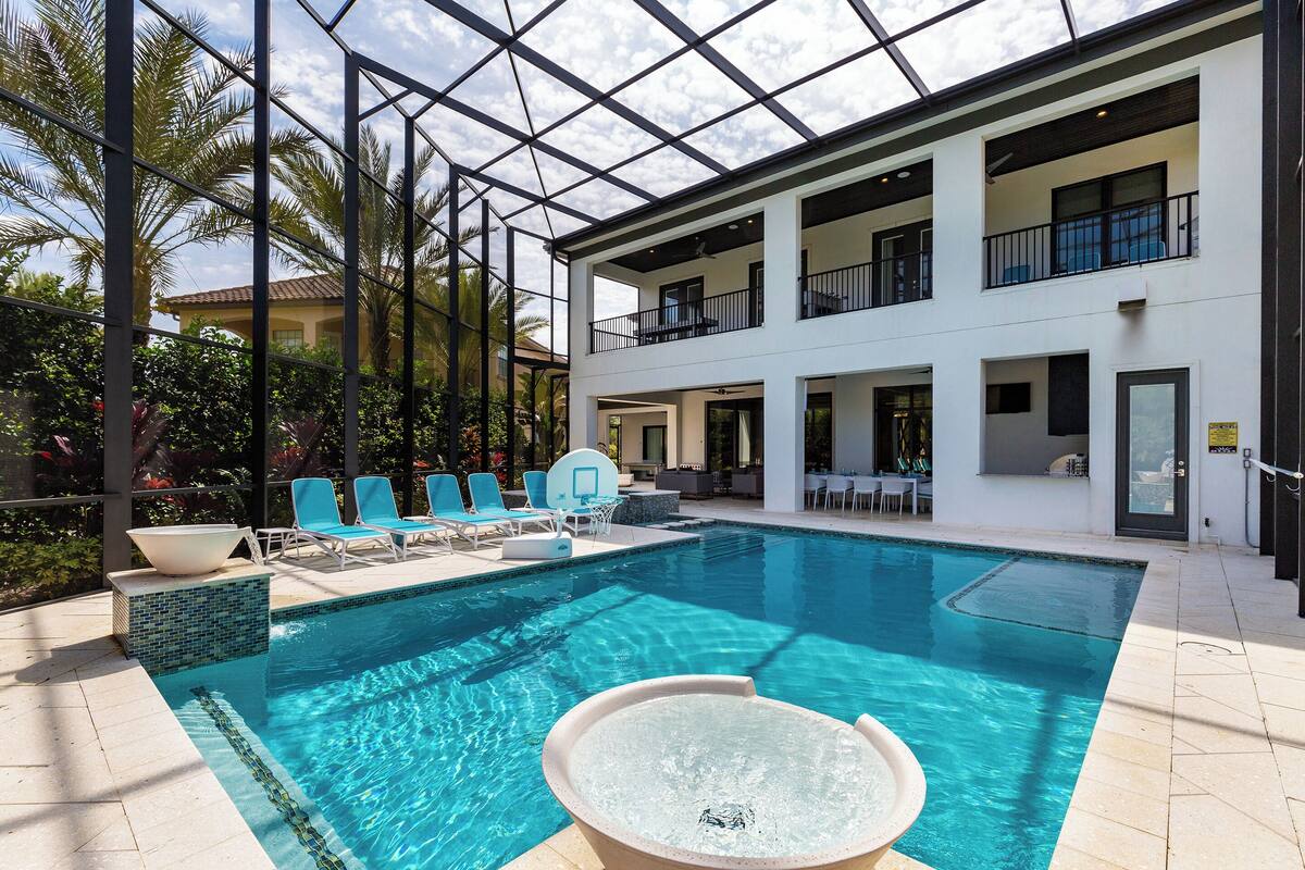 A swimming pool with a hot tub, lounge chairs, and a covered area with a glass ceiling.