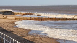 A beach with a wooden sea defense structure, a concrete barrier, and a railing along the shore. - Sea Spell Loft (Hornsea)