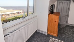 A room with a view of the sea, a wooden cabinet, and a door. - Sea Spell Loft (Hornsea)