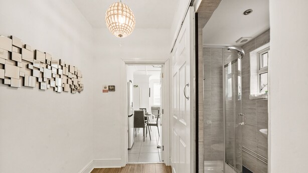 A modern hallway with a wooden floor, a glass shower, and a chandelier. - Modern 4BR Victorian Home near Luton Airport (Luton)