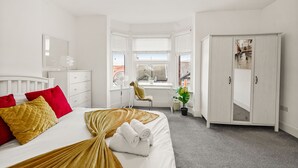 A bedroom with a bed, a desk, a wardrobe, and a window with blinds. - Modern 4BR Victorian Home near Luton Airport (Luton)