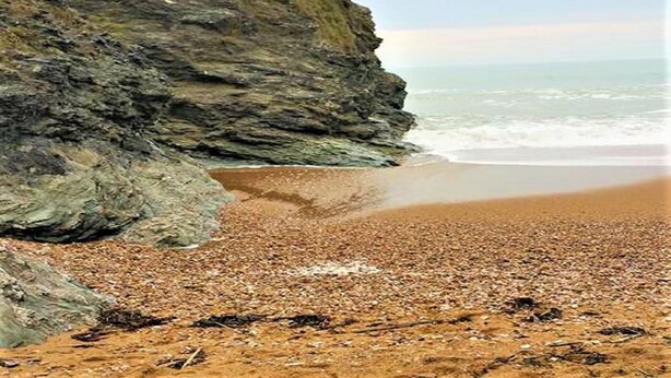 Une plage rocheuse avec une falaise et une vue sur l’océan.
