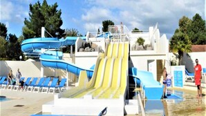 Un parc aquatique doté de nombreux toboggans et d’un espace piscine avec des chaises longues.