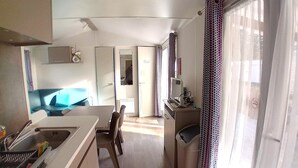 Une cuisine compacte comprenant un évier, un coin repas avec une table et des chaises, et un petit espace de travail équipé d’un ordinateur.