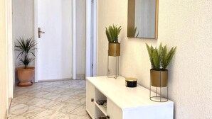 A hallway with a white console table, two potted plants, a mirror, and a door. - Spacious 2-Bed Apartment in Cavtat (Cavtat)