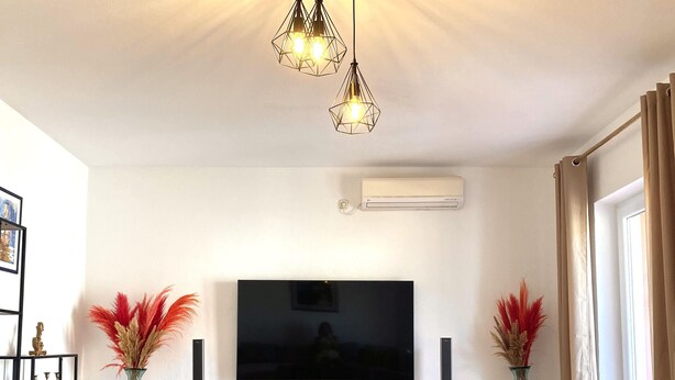 A modern living room with a flat-screen TV, wooden flooring, a large rug, and decorative vases. - Spacious 2-Bed Apartment in Cavtat (Cavtat)