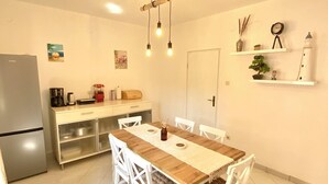 A kitchen with a wooden table and white chairs, a refrigerator, and a coffee machine. - Spacious 2-Bed Apartment in Cavtat (Cavtat)