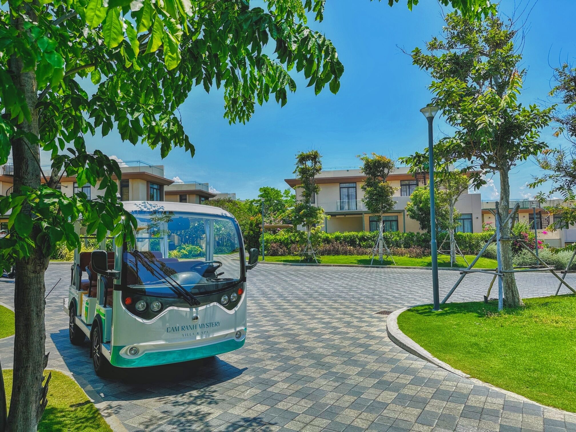 A bus parked on a paved driveway with a building in the background.