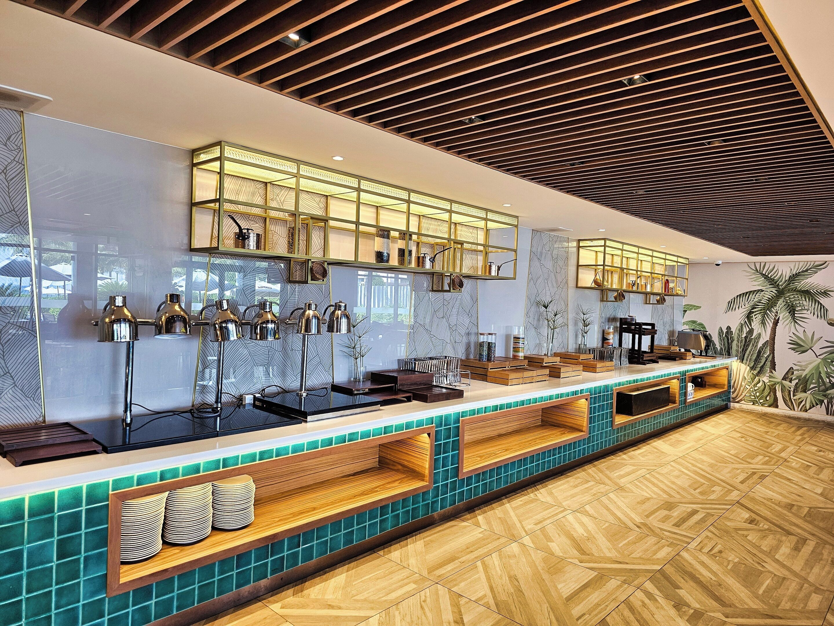 A modern bar area with a long counter, multiple pendant lights, and a patterned wall.