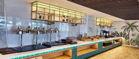 A modern bar area with a long counter, multiple pendant lights, and a patterned wall.