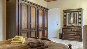 Un dormitorio con un armario grande, una cómoda y una cama con toallas dobladas.