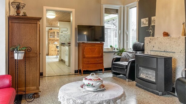 Una sala de estar con chimenea, televisor y comedor con mesa para dos.