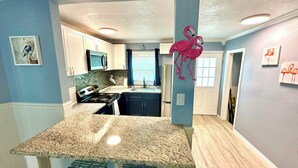 A kitchen with granite countertops, a stove, and a refrigerator.