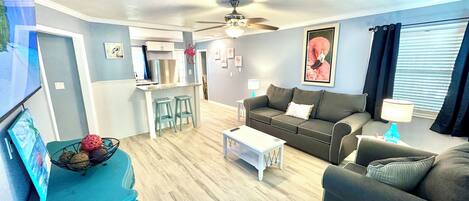 A living room with a grey sofa, a white coffee table, and a teal side table with a picture frame.