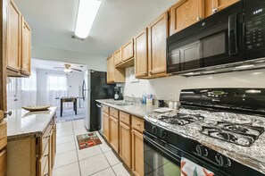 A kitchen with wooden cabinets, a black stove, a microwave, and a refrigerator.