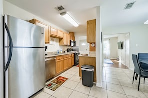A modern kitchen with stainless steel appliances, wooden cabinets, and a tiled floor.