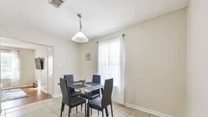 Un comedor con una mesa y sillas, una lámpara en el techo y una ventana con cortinas.