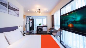 A hotel room with a bed, a desk, a chair, a television, and a view of the aurora borealis.