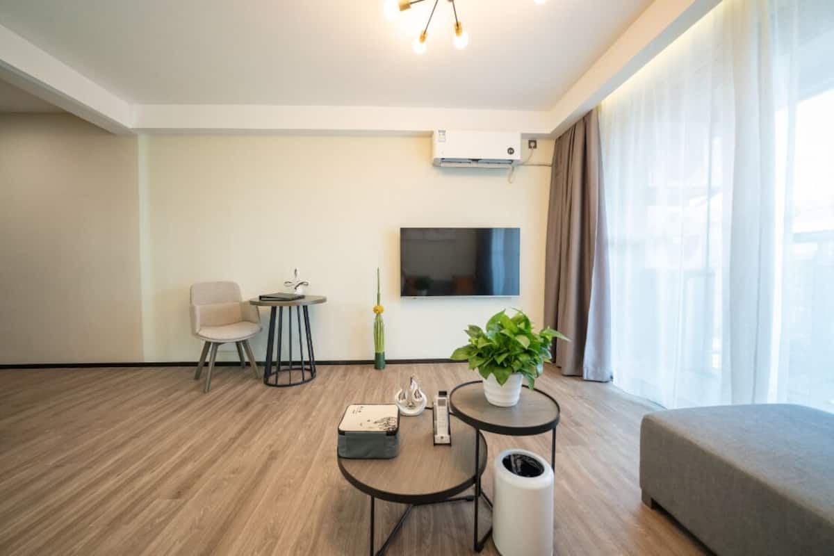 Una sala de estar moderna con un televisor de pantalla plana, un sofá, una mesa de comedor y una planta en maceta.