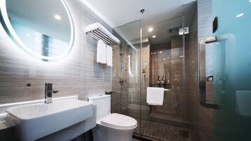 Een moderne badkamer met een douchecabine van glas, een ronde spiegel en een witte wastafel.