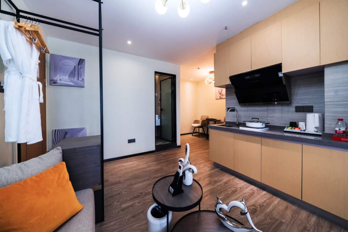 Una cocina moderna con armarios de madera, una campana extractora negra y una zona de comedor con mesa y sillas.