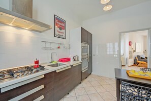 Une cuisine moderne dotée d’une cuisinière à gaz, d’appareils électroménagers en acier inoxydable et d’un dosseret carrelé.