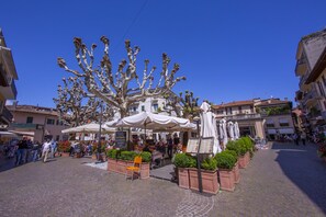 Una piazza lastricata con posti a sedere all'aperto, una fontana e edifici circostanti.