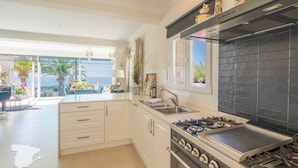 A modern kitchen with white cabinetry, a gas stove, and a large window overlooking a scenic view.