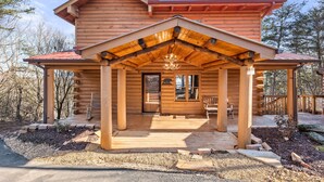 A log cabin with a covered porch, a wooden deck, and a view of the surrounding forest. - Above & Beyond - Cabin w/ Massive Views Near Helen (Cleveland)