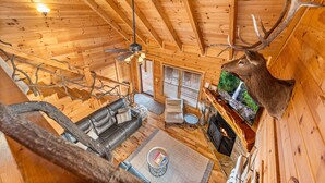 A log cabin interior with a fireplace, leather sofa, and a mounted deer head. - Above & Beyond - Cabin w/ Massive Views Near Helen (Cleveland)