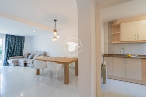 Un salon moderne avec une table et des chaises en bois, un canapé et un coin cuisine équipé de placards et d’un évier.