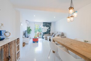 Eine moderne Küche mit weißen Schränken, einem Holztisch und einer Pendelleuchte.