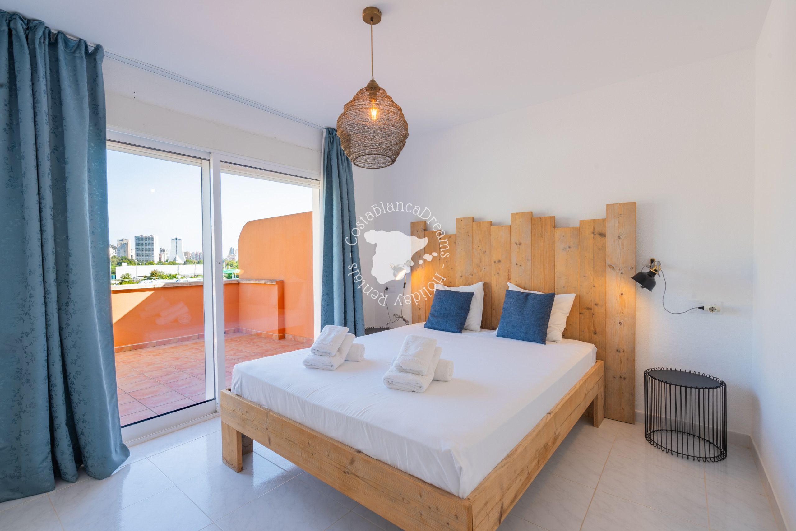 Ein Schlafzimmer mit einem hölzernen Bett, einem großen Fenster und Blick auf die Stadt.