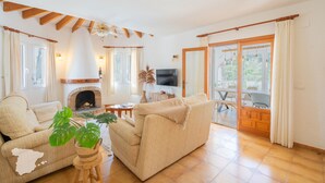 Ein Wohnzimmer mit einer Couch, einem Kamin, einem Fernseher und einem Essbereich mit Tisch und Stühlen.