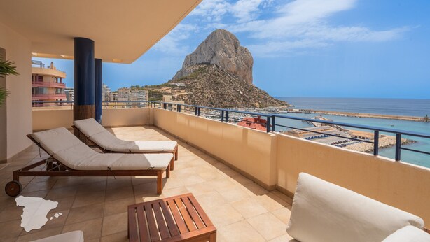A balcony with lounge chairs and a table, overlooking a coastal view with a prominent rock formation. - CostaBlancaDreams - Maroen in Calpe (Calpe / Calp)